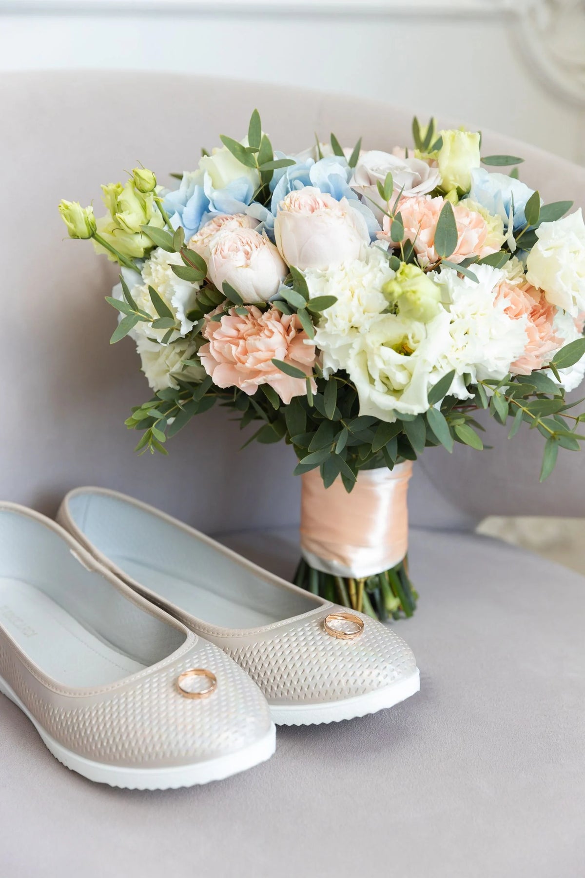 A seasonal bouquet beside wedding shoes.