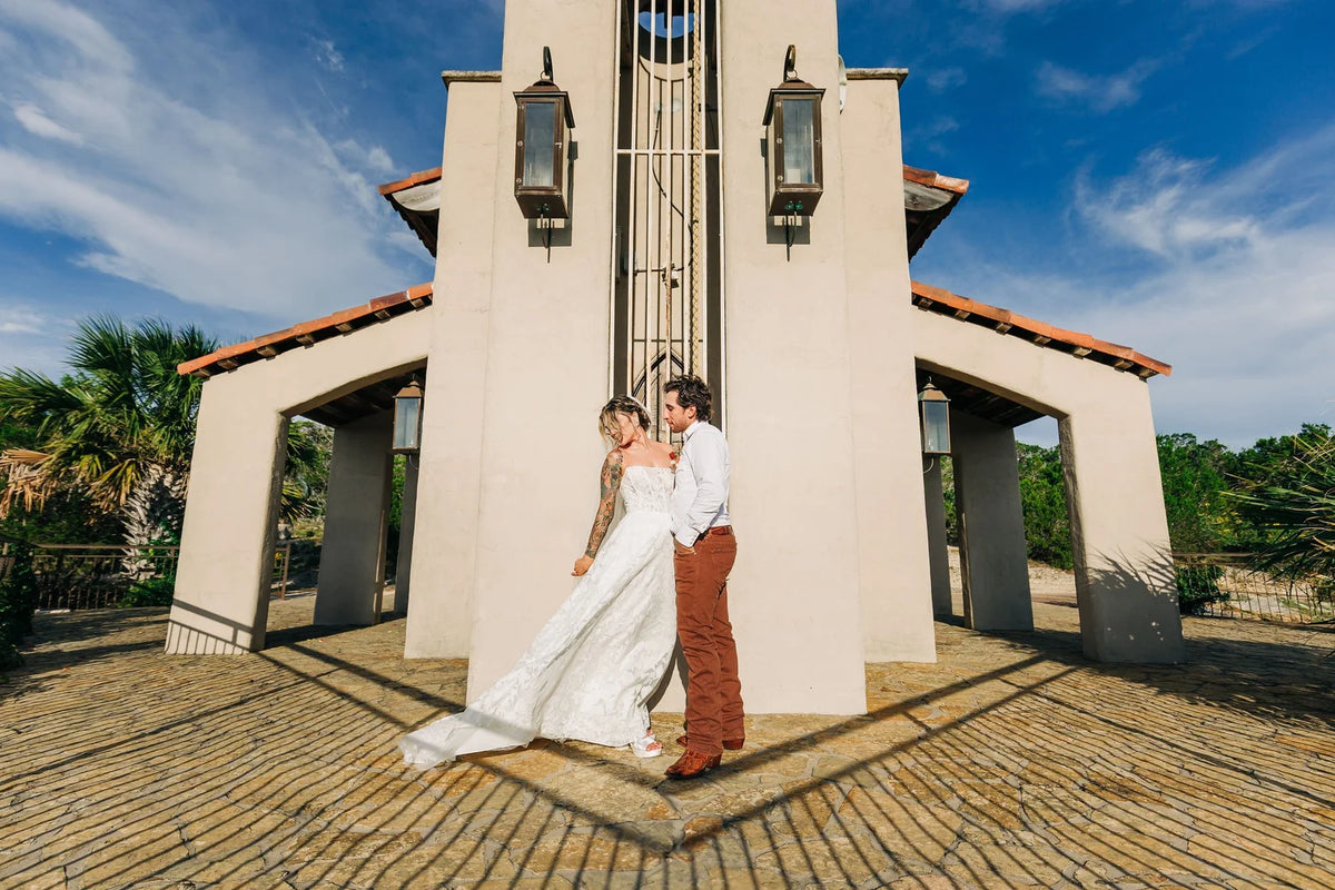 A couple standing together outside the sunlit stone entrance at Chapel Dulcinea.