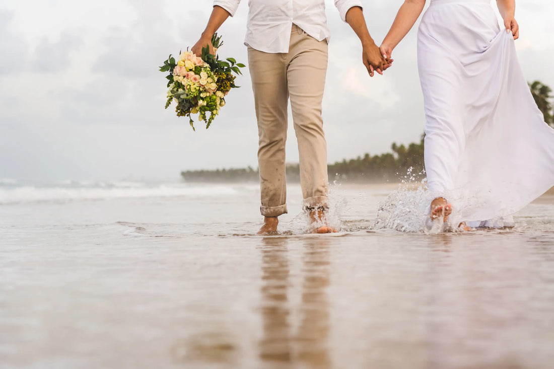 A newlywed couple walking together along a quiet beach.