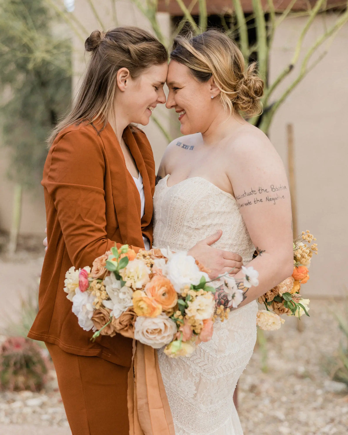 Two newlyweds in rust and ivory share a quiet moment with their bouquet.