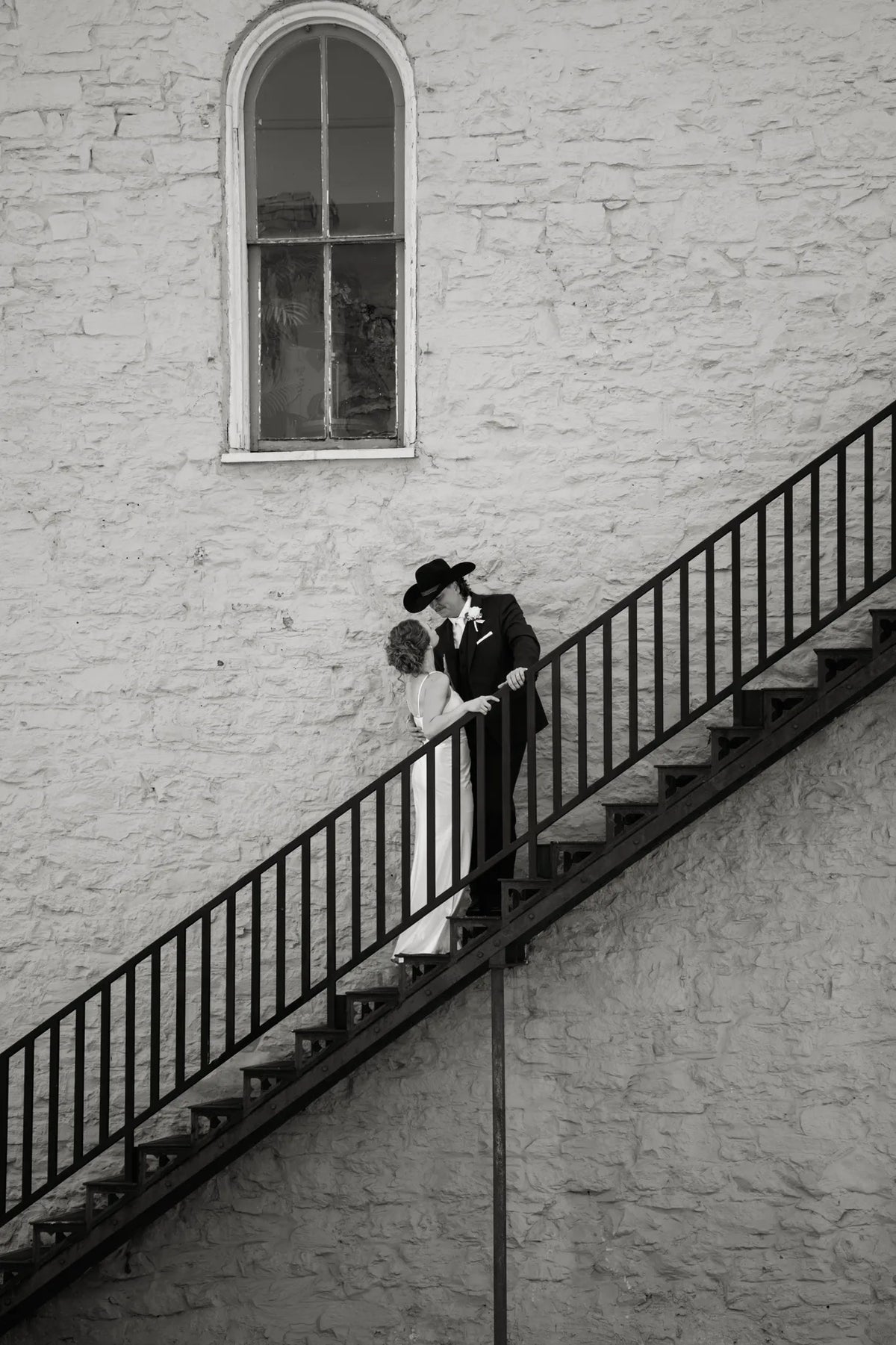 A newlywed couple walking together on a sunlit limestone staircase in Austin.
