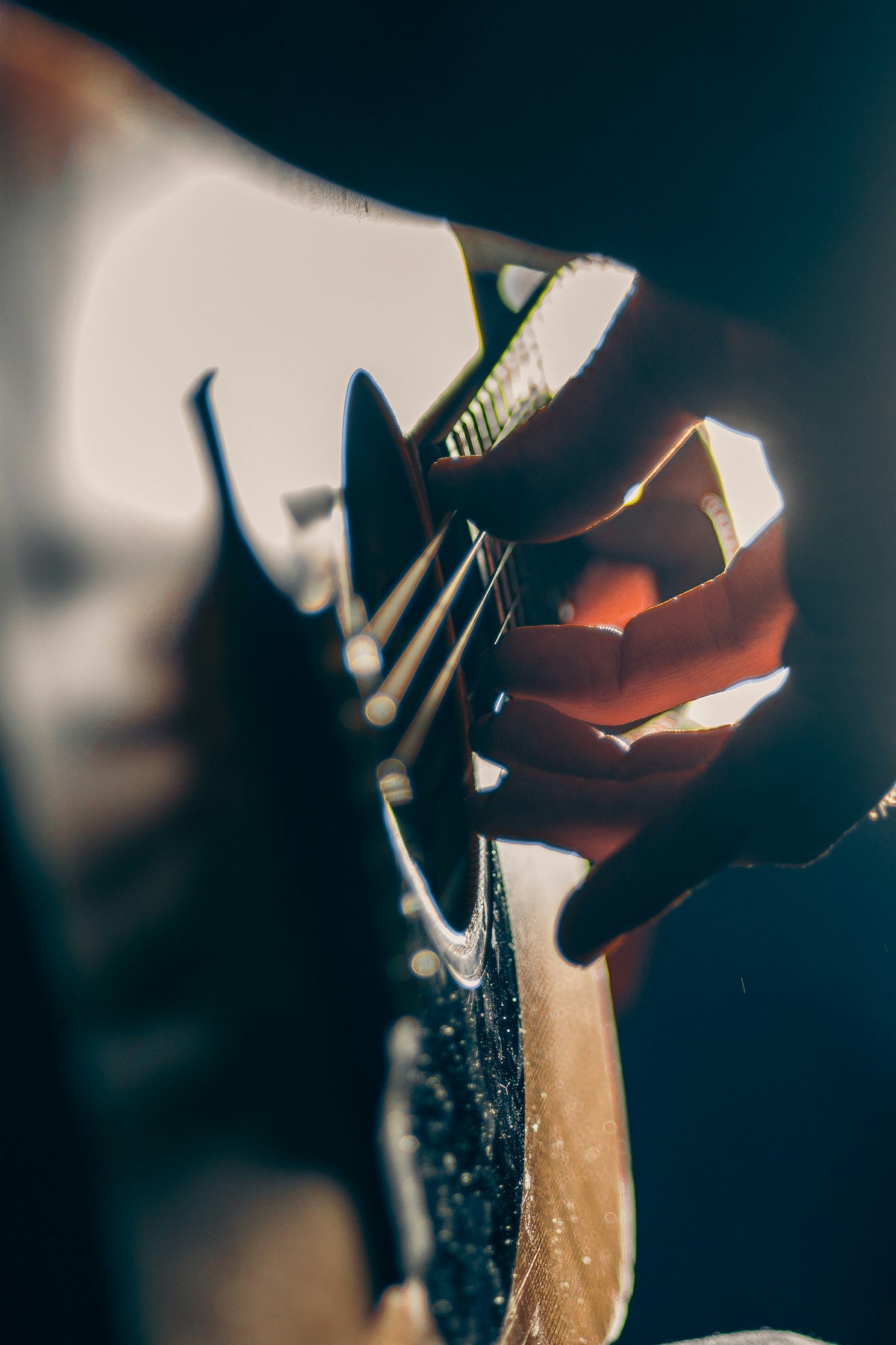 Hands playing an acoustic guitar in warm light.