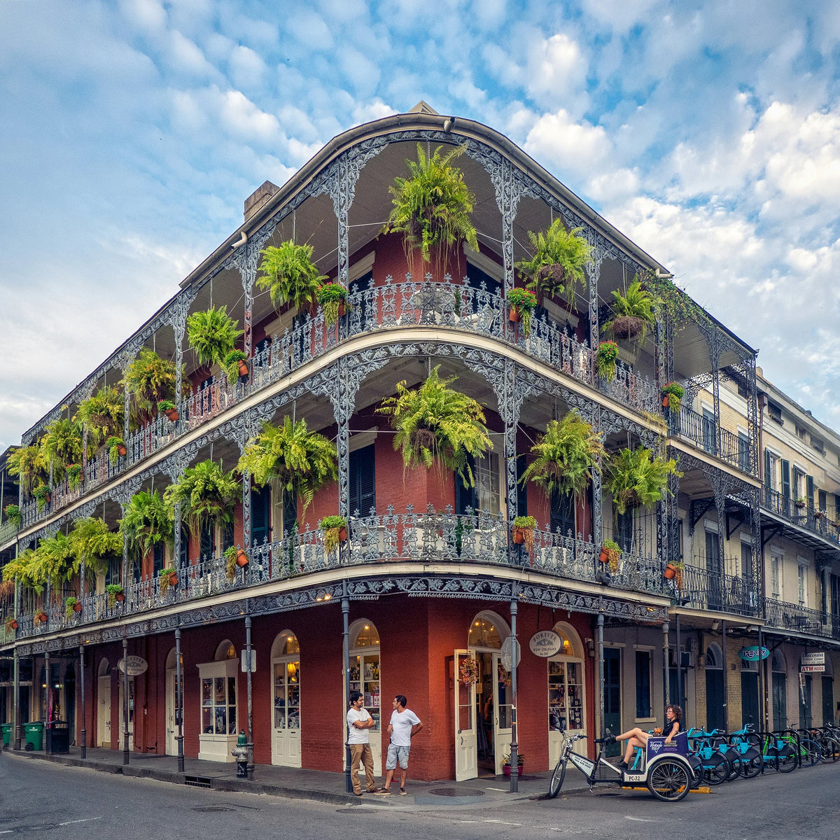 Ferns cascade from an ornate French Quarter corner balcony in New Orleans.