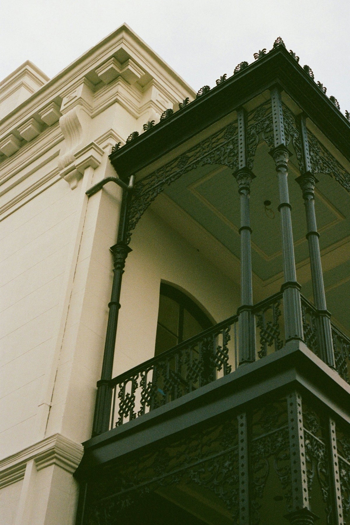 Green ironwork balcony against a cream facade in the Garden District, New Orleans. Photo: Topher McKee.