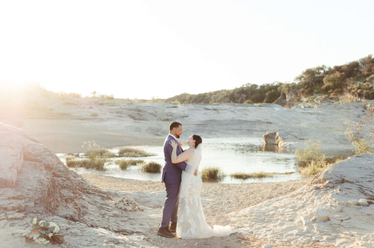 A couple exchanges vows beside a sunlit limestone river.