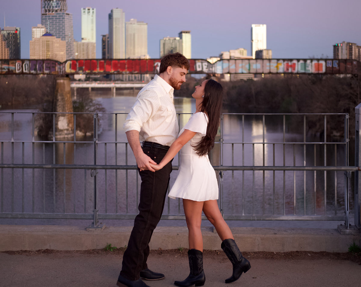 A couple celebrating at Butler Park with the Austin skyline behind them.